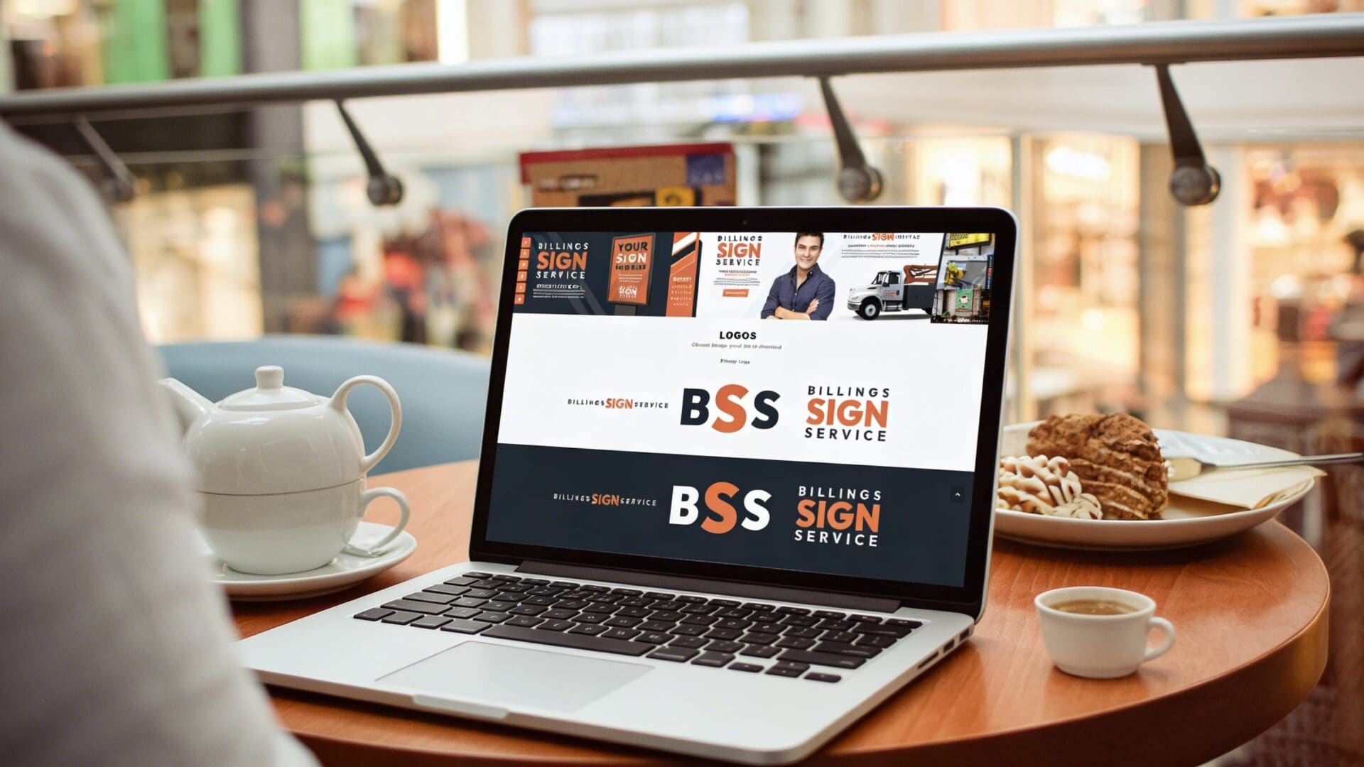 Laptop displaying brand guide essentials with signage and branding elements.